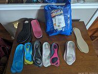 All shoe insoles in different colors and styles, laid out with the blue pouch in the background