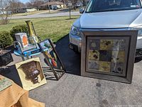 Lot contents including 2 metal wall hangings, metal vase in box, framed mixed pattern wall decor, salt lamp, computer stand, round blue table