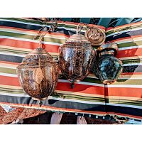Three crackled glass mid century lights shown together on striped fabric background, showing amber purple crackled glass globes and metal mounting hardware.