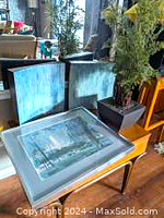 Overall view of lot including Ralph Avery print, two blue framed wall art pieces on a table, and the artificial plant in a pot.