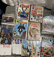 Stack of various Marvel comic books including The Mighty Thor, Web of Spider-Man, Marvel Age and Babylon 5 comics laid out on fabric surface