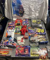 Overview of NASCAR diecast cars, flags, Hot Wheels, and other small memorabilia spread on a surface.
