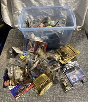 Plastic bin and spill of numerous NASCAR diecast cars mostly in original packaging, some loose, mostly new condition