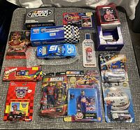 Top-down view of all NASCAR diecast cars, action figures and promotional packaging laid out on a patterned fabric surface.