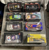 Top-down view showing all 8 cars in boxed packaging arranged on a black table.
