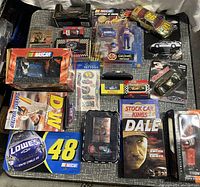 NASCAR collectibles including diecast cars, DVDs, collectible figurines, and trading cards displayed on a table.