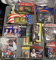 Photo showing NASCAR diecast cars in original packaging and some loose items on a silver surface including Mark Martin and others.