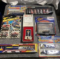 Top-down photo showing various NASCAR collectible items including die-cast micro transporters, magazine, and Blackboxed cars.