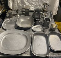 Full view of pewter set including plates, pitchers, cups, candlesticks, shallow bowl, and decorative mold