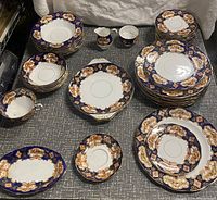 Photo showing the full variety of plates, cups, bowls, and platters in cobalt blue and gold floral Royal Albert bone china set.