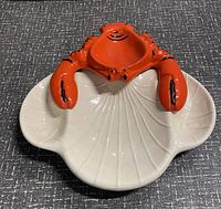 Top view image showing the cream-colored ceramic tray with lobstered shell shape and attached bright orange lobster figurine on top.