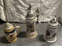 Three German beer steins placed side by side showing their overall size and decor