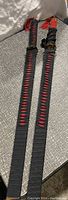Two black and red wrapped replica samurai swords side by side on a carpeted floor