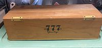 Full view of rectangular wooden box with hinged lid and '777 By Jesus Fuego' branding on front.