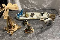 Collection of animal figurines displayed on a surface with a decorative tray in the background and wooden Christmas pyramid on side.