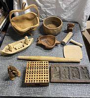 All wooden items in one shot, showing a basket, bowls, carved figures, utensils, a lattice box, and a mold with carvings.