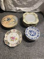 All four stacks of decorative plates; yellow floral, blue floral, pink floral with black lattice, and green & yellow floral border