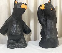 Two black ceramic bear figurines side by side, showing full bodies with orange snouts and ears