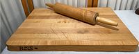 Top view of rectangular butcher block with wooden rolling pin on top featuring surface scratches.