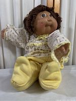 Front view of the doll seated, showing full body, clothing, and face.