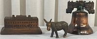 Three copper miniature pieces: a building, a donkey figure, and a Liberty Bell replica on a white background