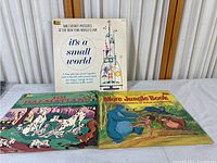 Three 12 inch Disney records with accompanying storybooks: It's a Small World, 101 Dalmatians, More Jungle Book.
