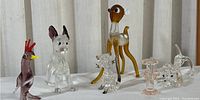 Glass miniatures collection showing all six figurines including bird, dog, deer, dog head, and two small abstract shapes on white fabric background