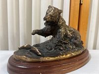 Side view showing the bear figure, fish, and wooden base with brass detailing.
