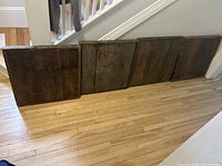 Four large solid wooden panels arranged side by side on a hardwood floor, showing their size and condition.