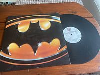 Vinyl record partially out of album cover showing Batman logo on front cover.