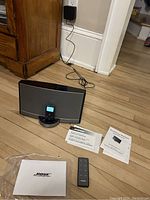 BOSE SoundDock Portable system with Apple iPod in dock, remote control and manuals on floor