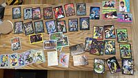 Overview of all trading cards laid flat on a wooden surface. Includes DC Comics, Ghost Rider, Simpsons, 90210, Batman and Monster in My Pocket trading cards.
