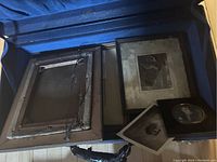 Open steamer trunk showing old framed photos and loose vintage photo prints inside