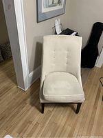 Front view of the light beige upholstered accent chair showing button tufted backrest and cushion seat.