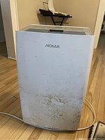 Front view of white NOMA dehumidifier showing branding and dirt marks on lower panel.