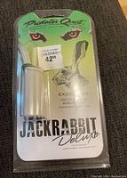 Front of the pack showing the Predator Quest Jackrabbit Deluxe Distress Call in clear plastic casing with green header card and orange predator eyes graphic.