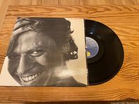 Photo of Robert Palmer's Riptide album vinyl record partially pulled out of its cover, showing black vinyl and original black-and-white cover with artist's face.