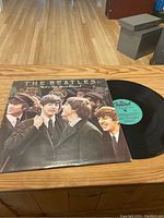 Photo of The Beatles Rock N Roll Music Volume 2 record sleeve and black vinyl on a wooden surface.