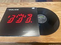 Front cover of The Police 'Ghost In The Machine' vinyl LP showing digital red stylized numeric album title design and black background.