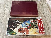 Two board games shown side by side - Diplomacy with maroon box, Risk with illustrated world map cover