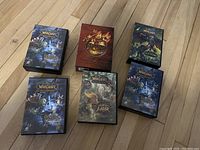 Six boxed sets of World of Warcraft Trading Cards displayed closed on wooden floor.