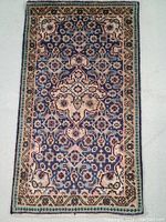 Top view of hand knotted Persian rug showing detailed floral/geometric pattern in blue and cream colors.