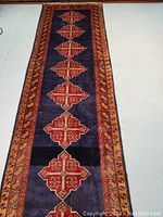 Overhead view of navy blue runner rug with red geometric medallions and multicolor borders