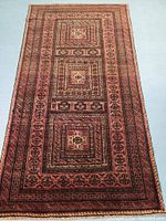 Full front view of Baluch wool rug laid flat