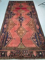 Full view of rug laid flat on light floor showing central field and border