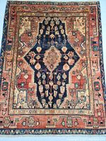 Full view of rug laid flat showing central medallion, navy field, red border and decorative motifs.