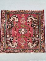 Front view of the hand knotted wool rug showing detailed historical design with horse motifs and central medallion on pink background.