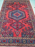 Full view of rug showing red field and central blue medallions in geometric arrangement