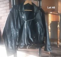 Front view of the vintage black leather biker jacket showing diagonal front zipper, zippered pockets, and epaulets.