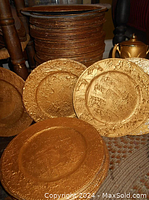 Stack of multiple Venetian plaster charger plates finished in old gold paint with textured surfaces, showing some wear and paint chipping